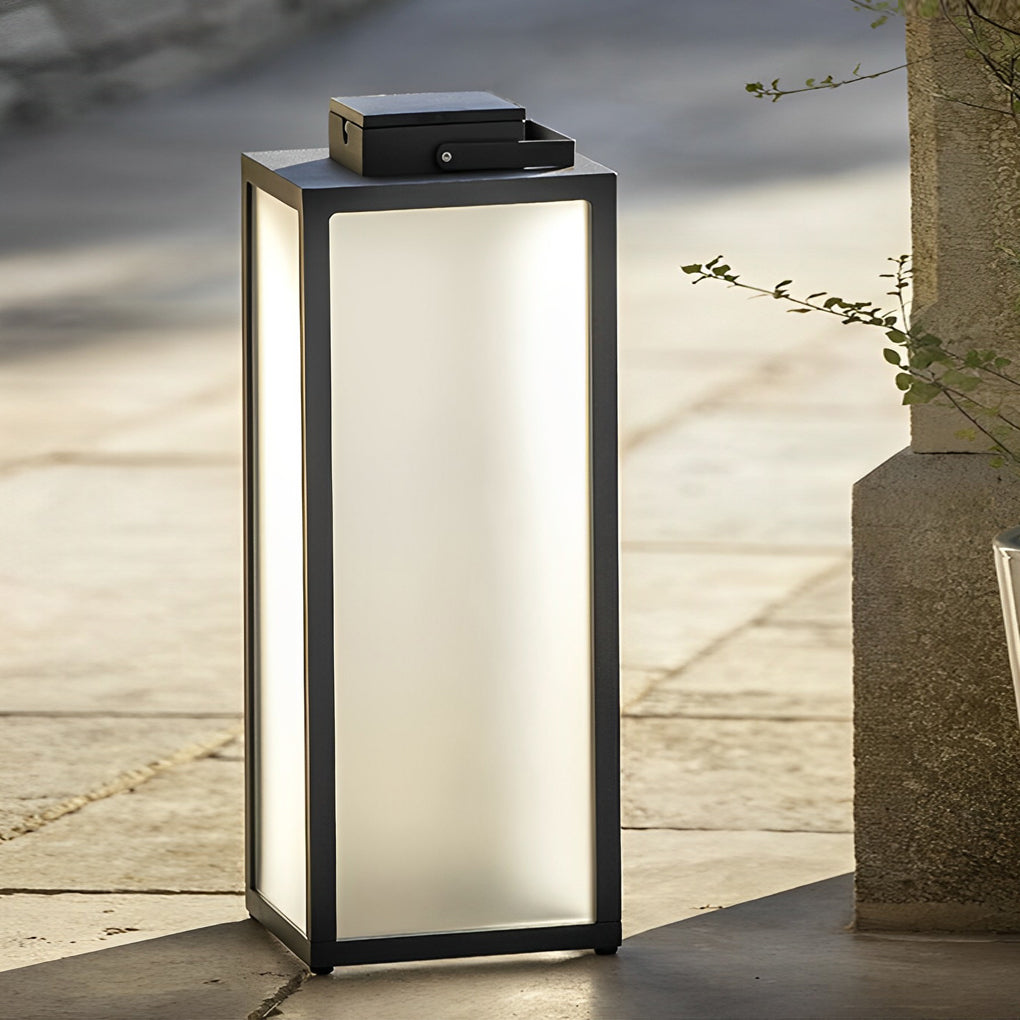 Square handheld lantern with sleek black frame beside tree in garden.