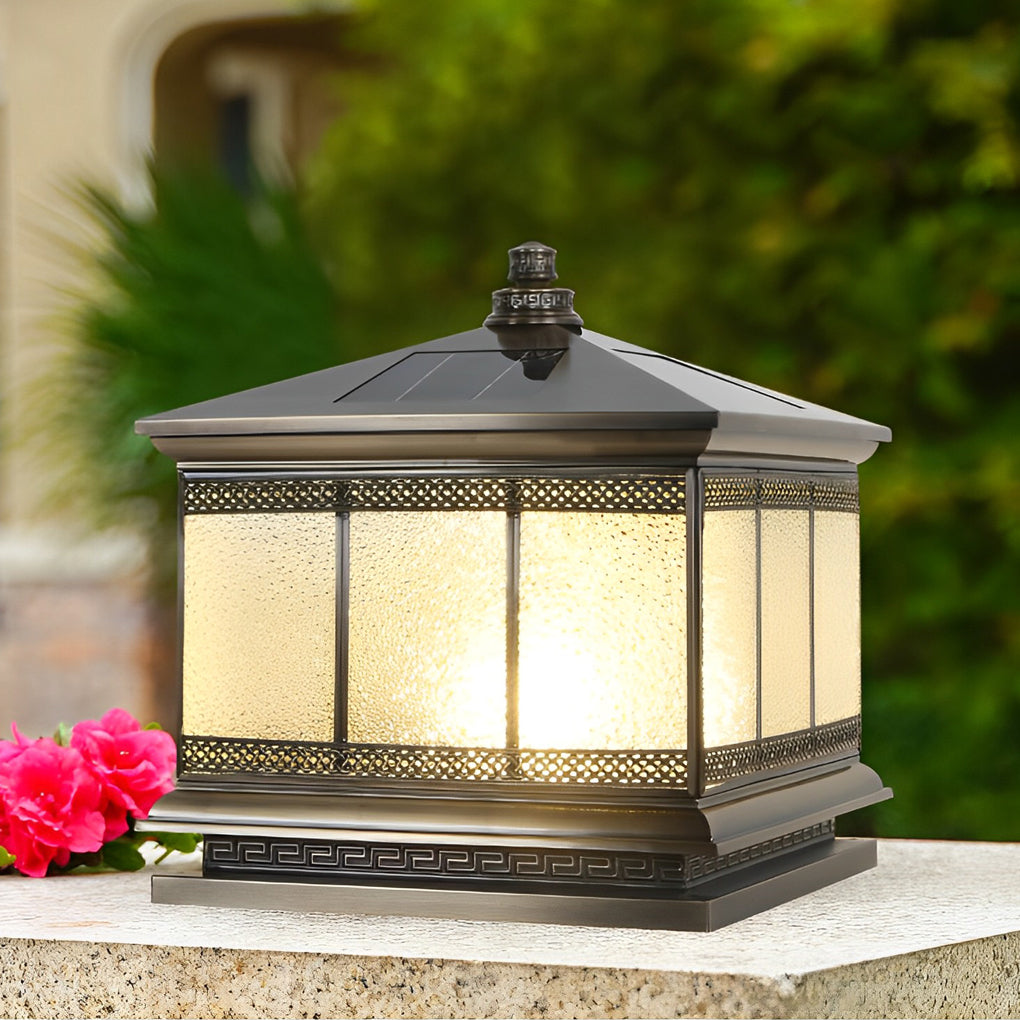 Square outdoor gate pillar light with frosted glass panels glowing in a landscaped yard.