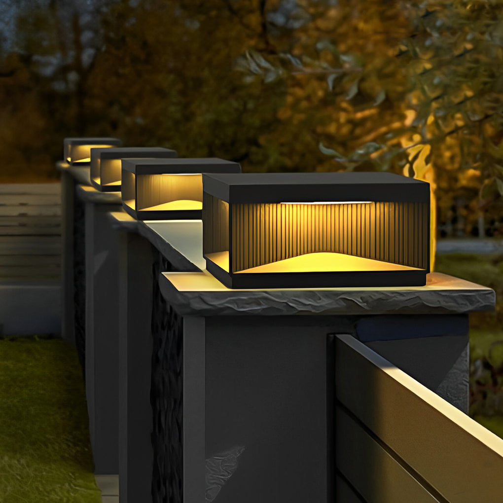 Square outdoor pillar lights aligned along fence pillars creating consistent outdoor boundary lighting.