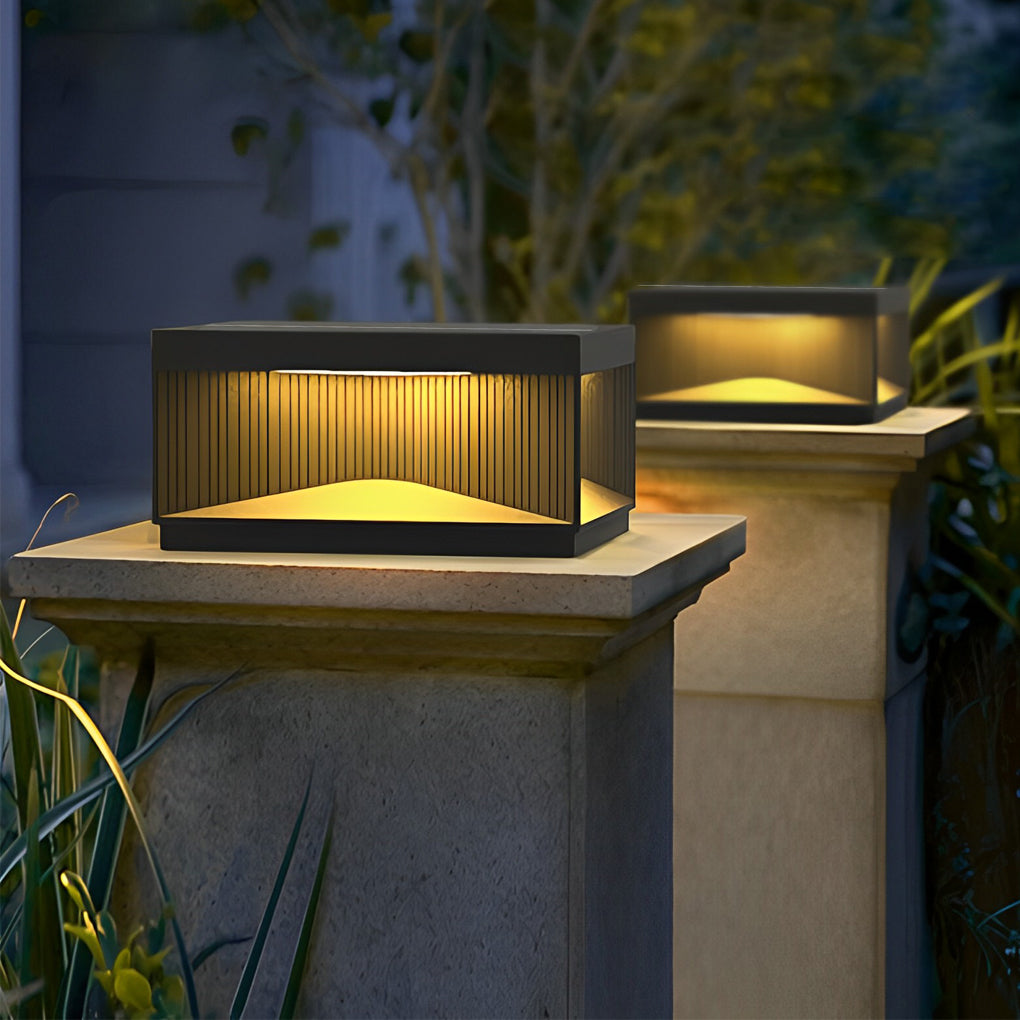 Square outdoor pillar lights installed on stone post providing warm ambient lighting in landscaped garden.
