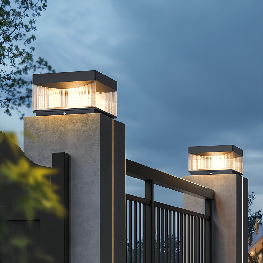 Square pillar lights installed on modern fence posts at twilight overlooking scenic landscape