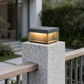 Square solar deck lights installed on concrete fence post providing warm outdoor accent lighting.