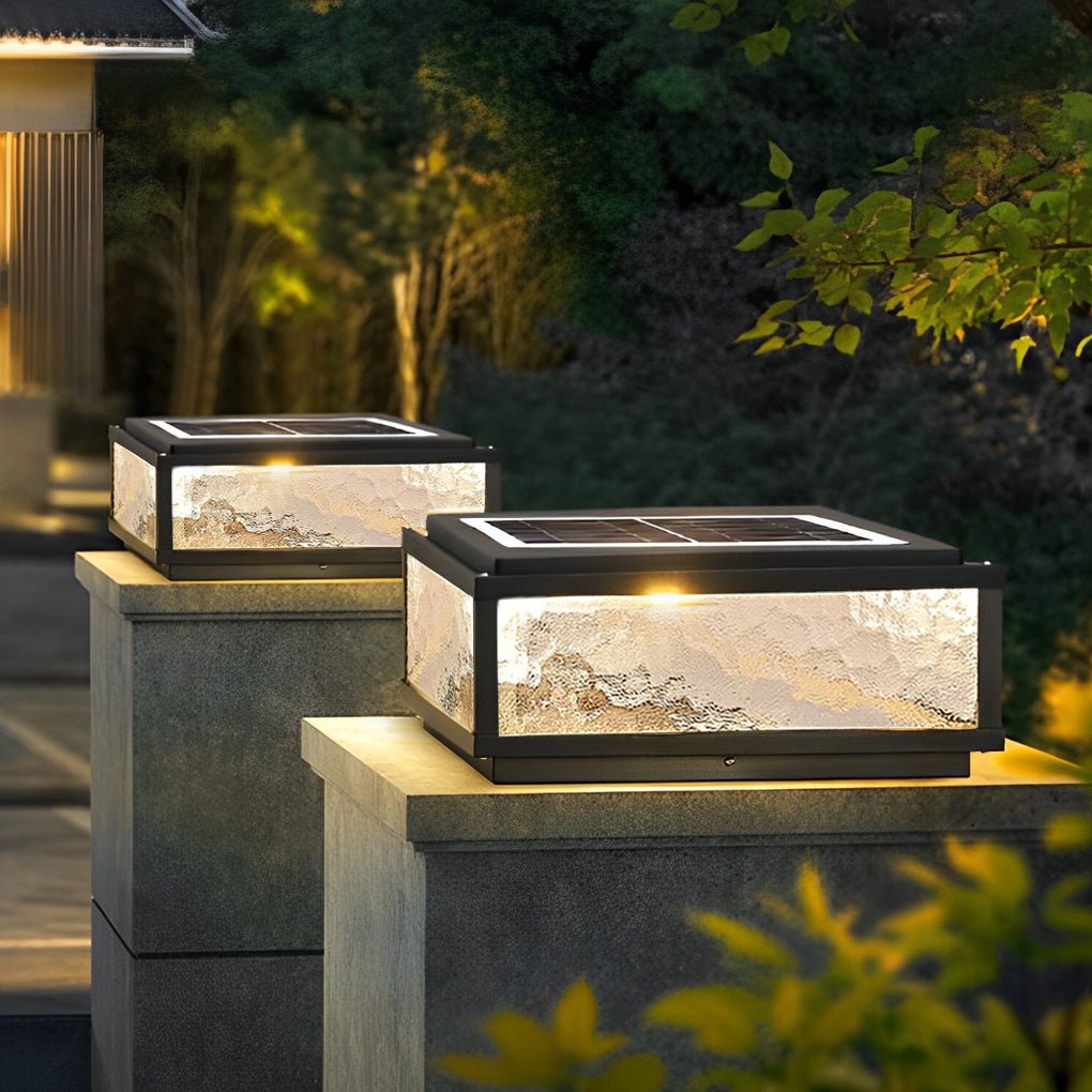 Square solar outdoor pillar lights illuminating stone posts in a landscaped garden at night.