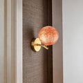 Red stained glass globe wall light mounted beside bed creating warm ambient lighting.