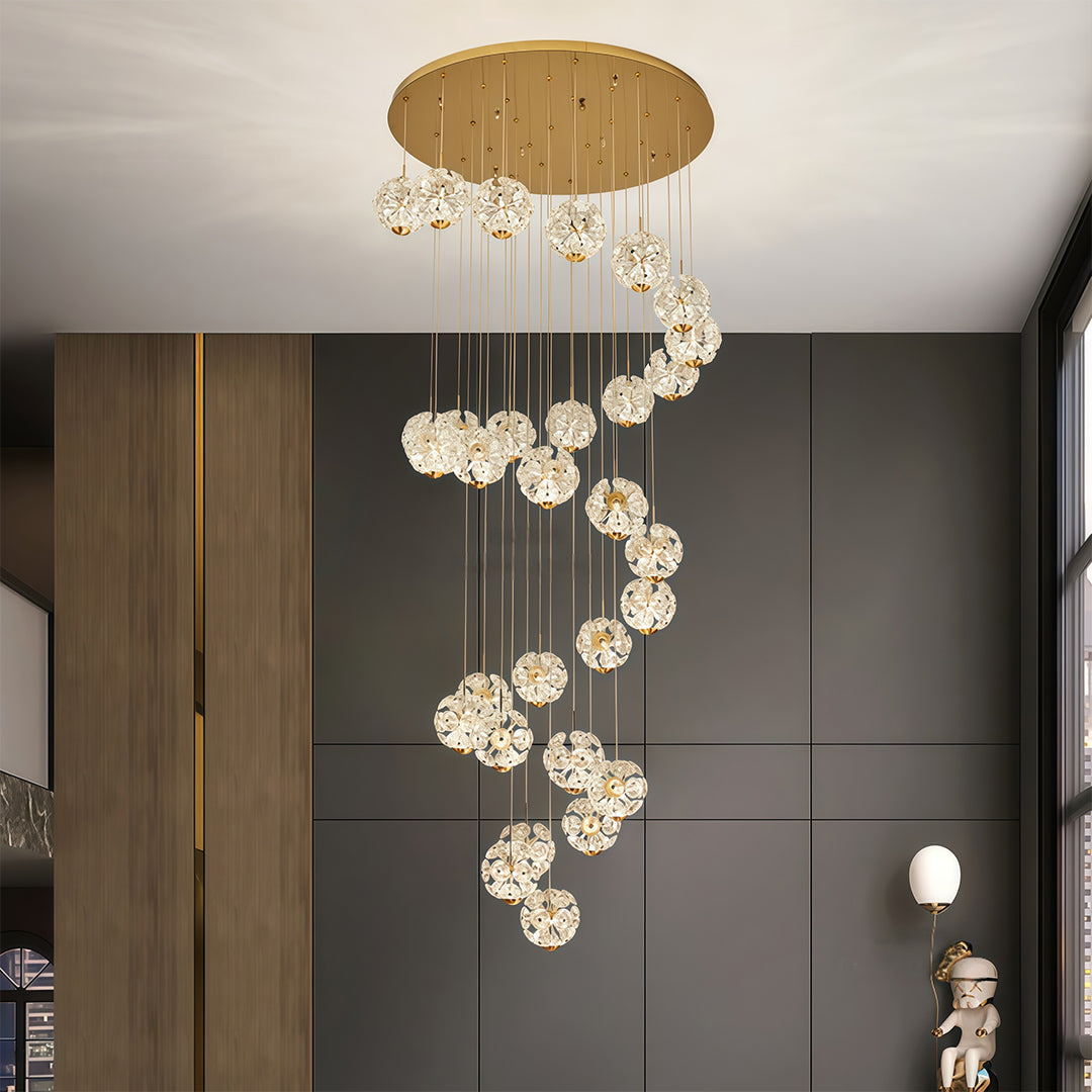 Spiral staircase crystal chandelier installed in a tall modern staircase area.