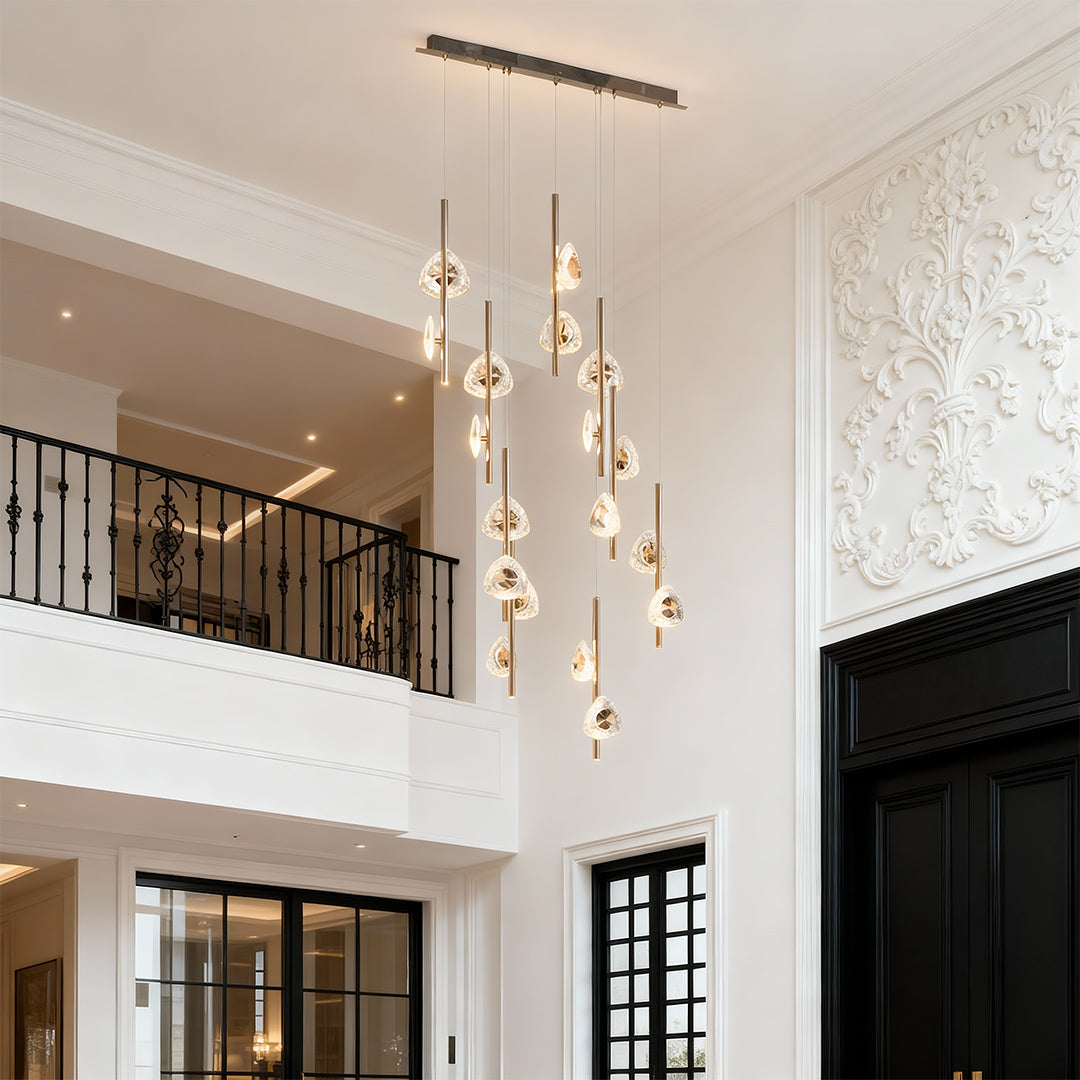 Staircase crystal chandelier providing sophisticated lighting in luxurious entryway with marble flooring and curved staircase