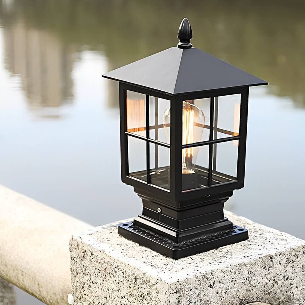 Stone light pillar with a black lantern, providing ambient illumination near a garden fence.