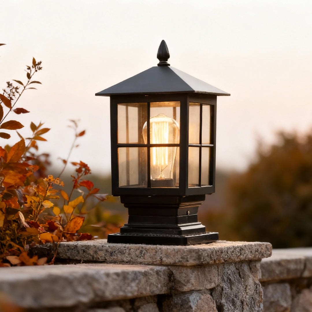 Stone light pillar with a black lantern, casting soft light in a garden during autumn.