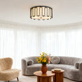 Stylish drum ceiling light flush mount with a black and gold metal cage, illuminating a cozy living room with a curved gray sofa.