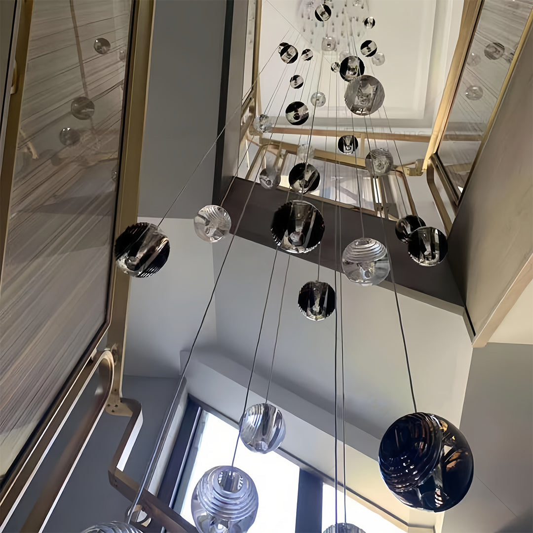Stylish metal pendant lights with smoked glass spheres, suspended above a reflective surface in a modern interior.