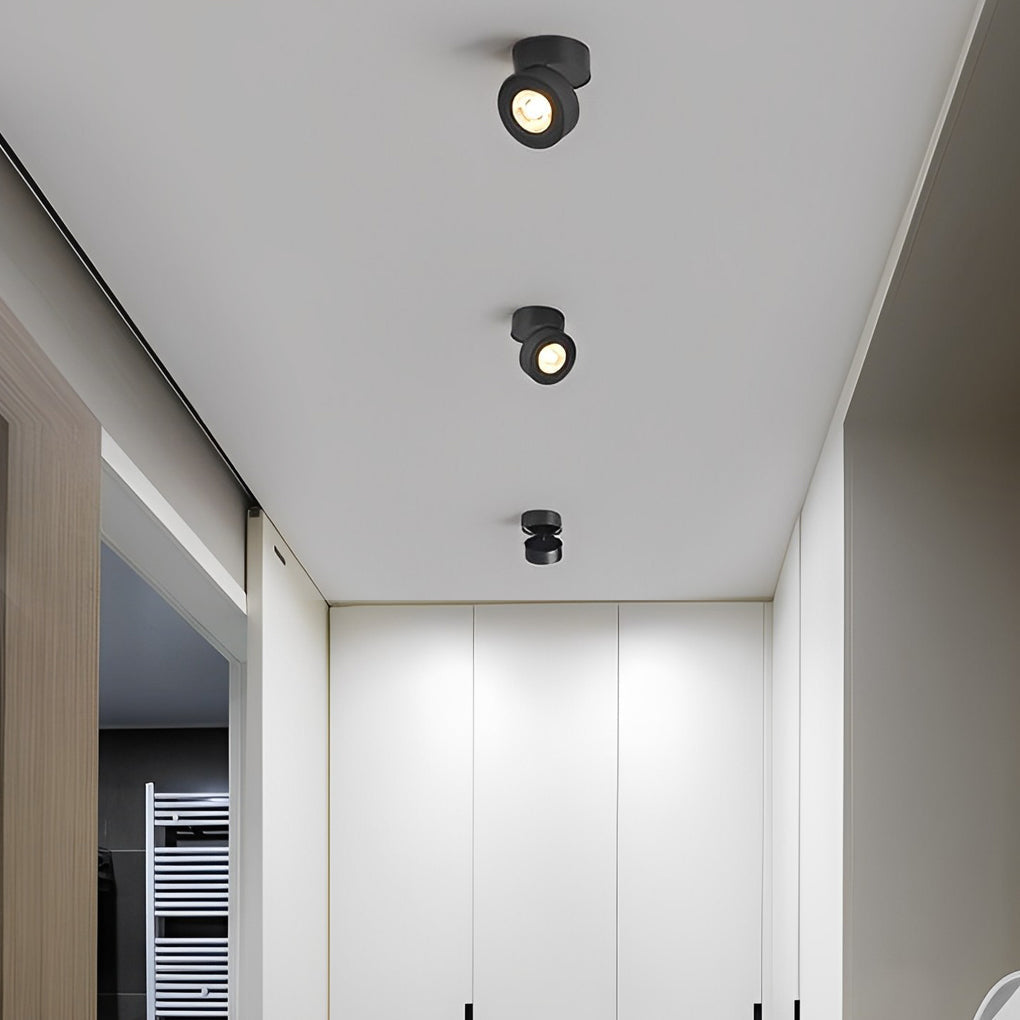 Surface mounted adjustable spotlight installed on a white ceiling, casting bright light in a hallway.