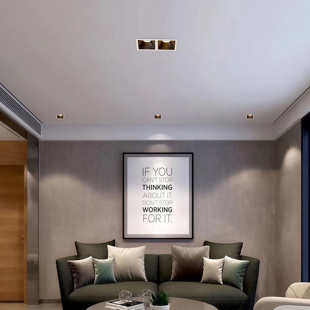 Surface-mounted square LED downlights providing accent lighting for a framed poster in a contemporary living room.