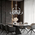 Swan chandelier installed above modern dining table in luxury interior.