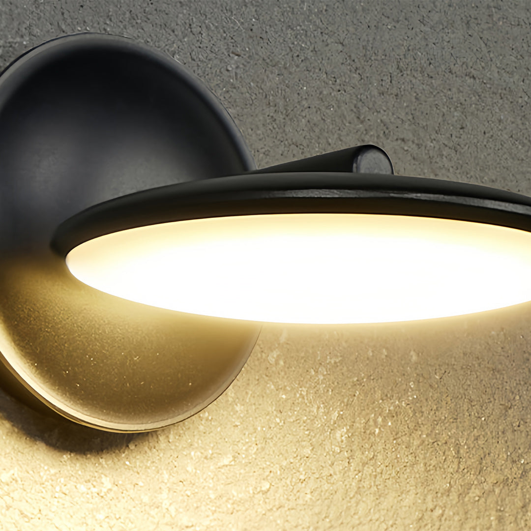 Close-up detail of swivel wall light showing black finish and curved LED panel casting warm glow