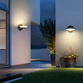 Swivel wall light mounted on modern house exterior at dusk with blue accent wall and landscaping