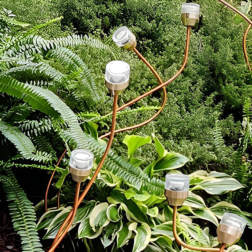 Syphasera standing lamp intertwined among ferns showing flexible stem design in greenery.