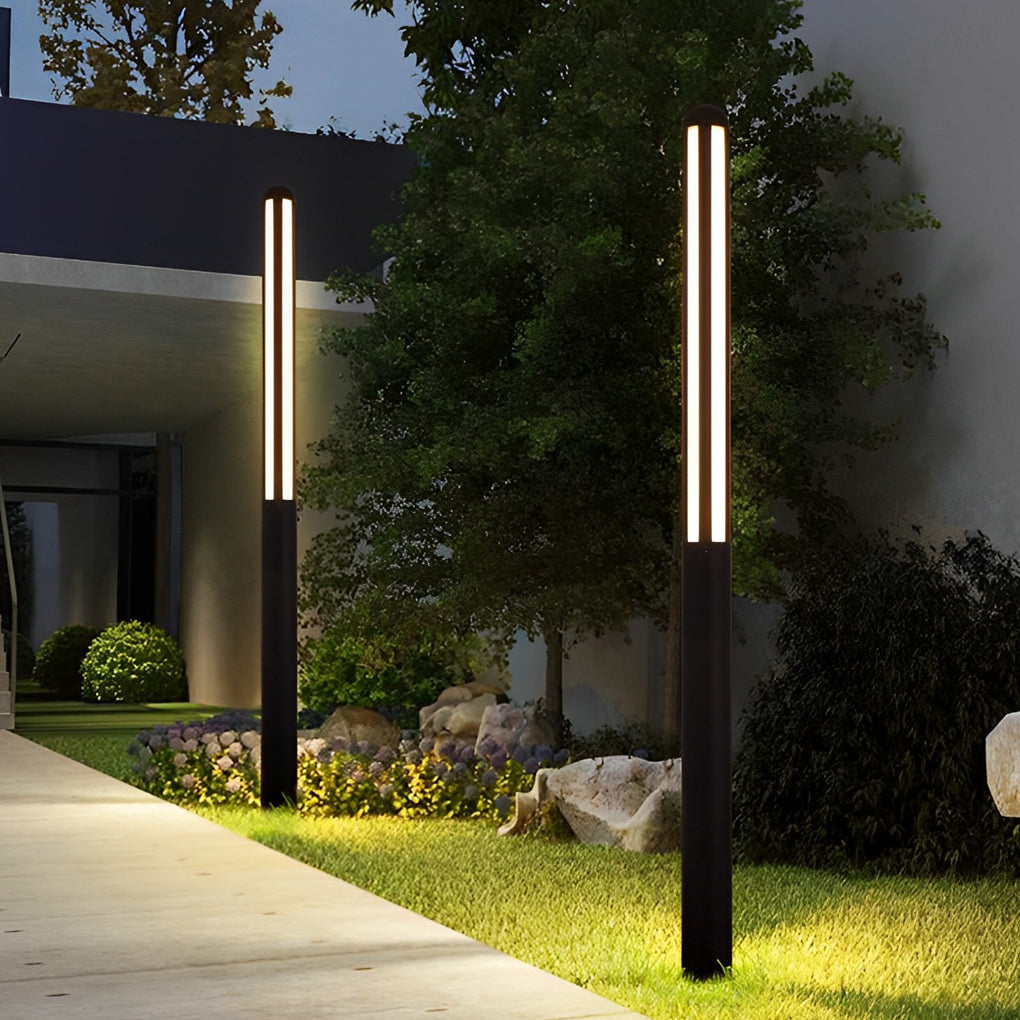 Tall garden bollard light illuminating driveway entrance with lush greenery.