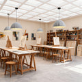 Multiple textured gray pendant light fixtures providing overhead illumination in a bright, organized art classroom studio.