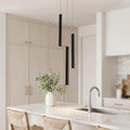 Trio of sleek black linear cluster pendant light fixtures over a luxury marble kitchen island.