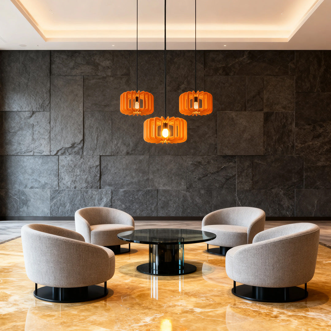 Trio of orange Nordic pendant lights illuminating a modern corporate lobby seating area.