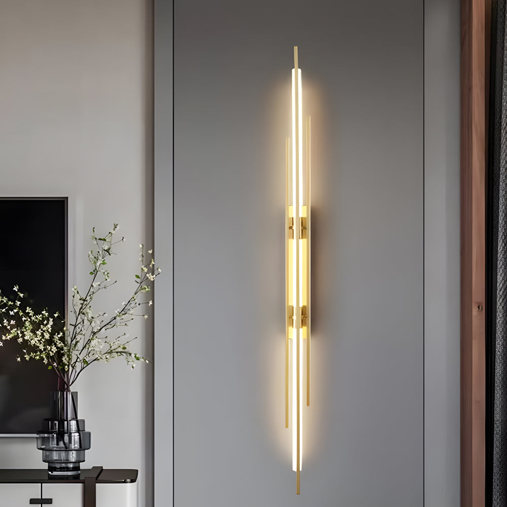 Vertical tube wall sconce installed above headboard for accent lighting.