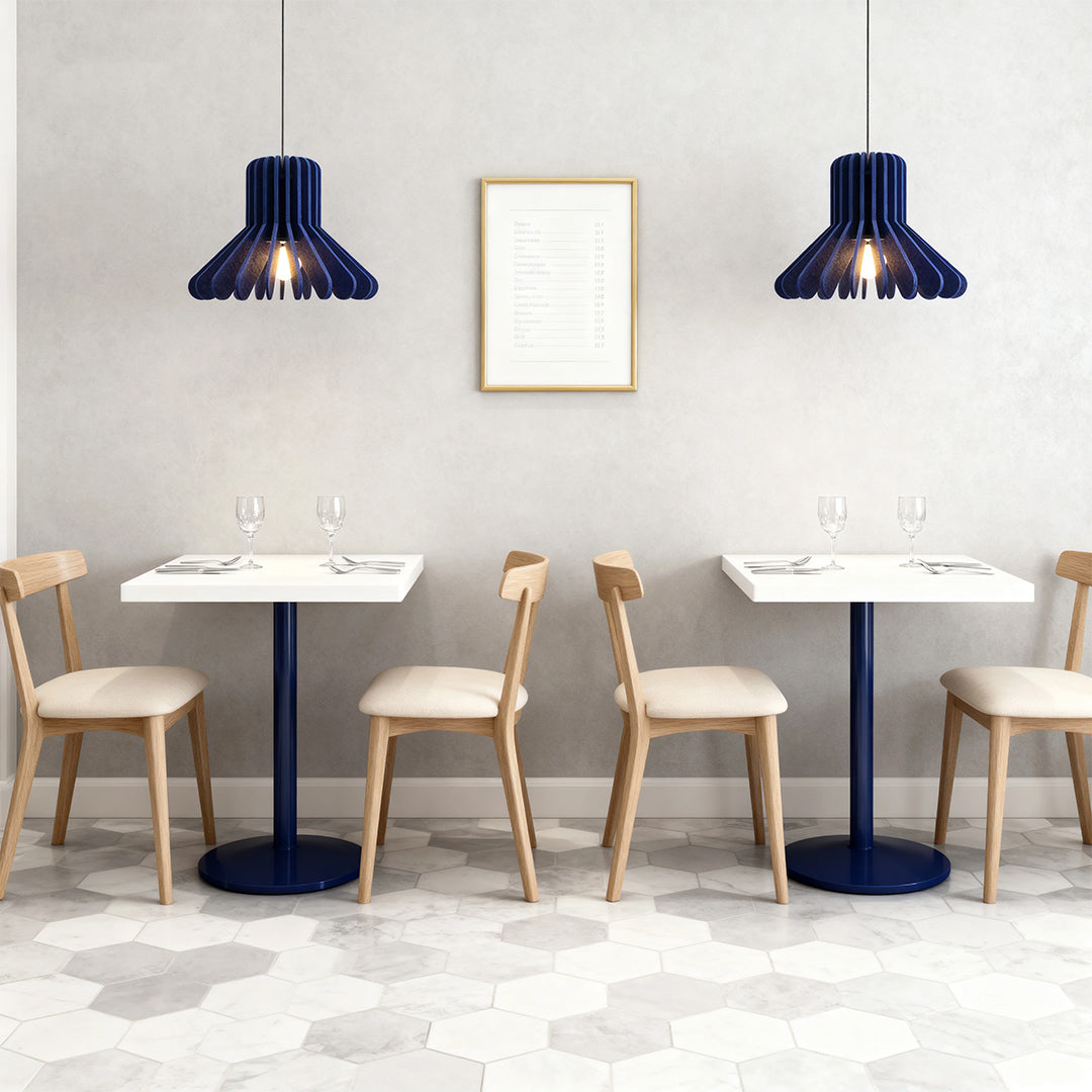 Two navy blue tiny pendant lights with decorative shades hanging above minimalist cafe tables