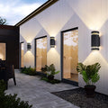 Up and down light wall sconce installed along a modern building exterior, casting warm illumination.