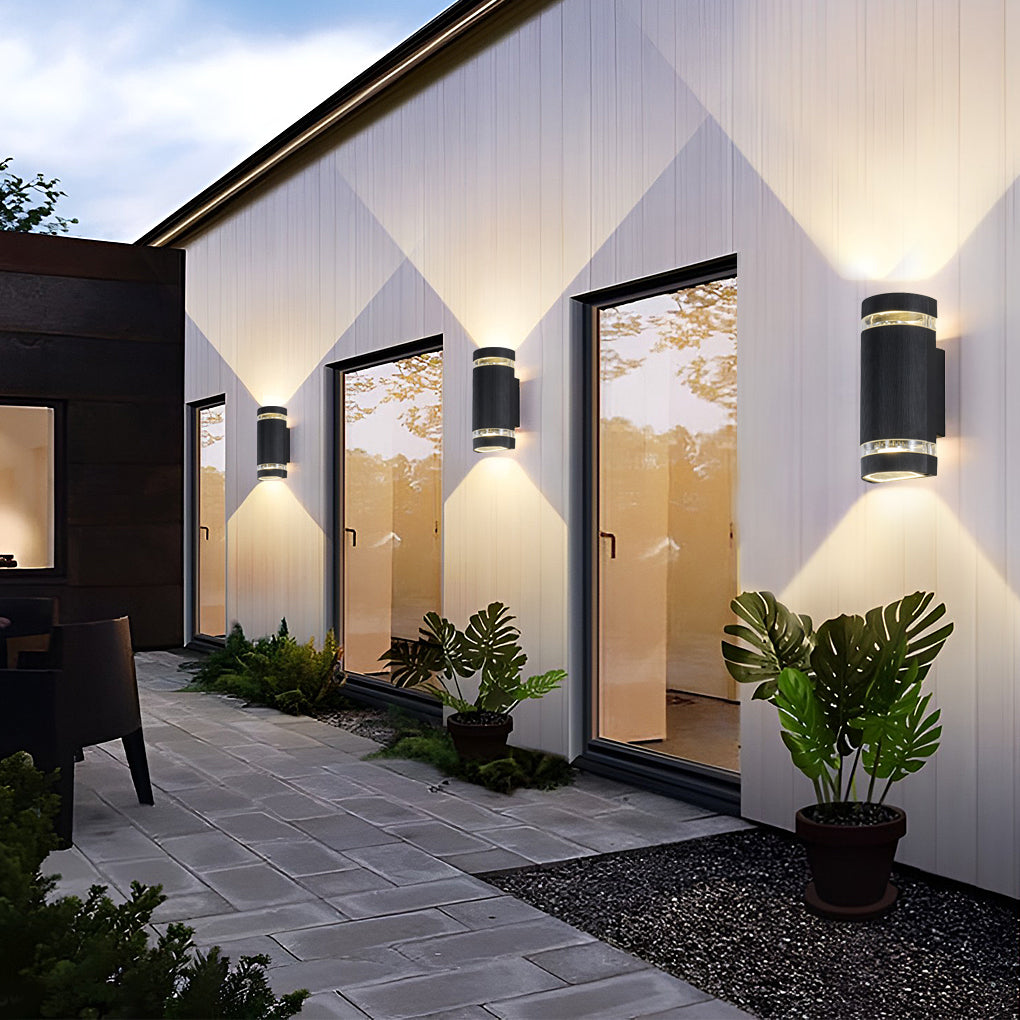 Up and down light wall sconce installed along a modern building exterior, casting warm illumination.