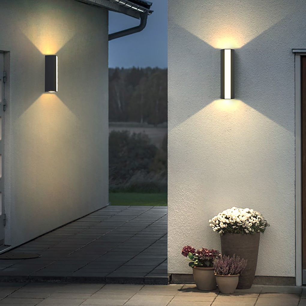 Up down cylinder sconce installed near a garden planter, highlighting textures and adding warmth to the exterior wall.