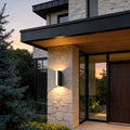 Up down cylinder sconce mounted on a modern home exterior, creating warm vertical light beams that accent stone and wood architecture.