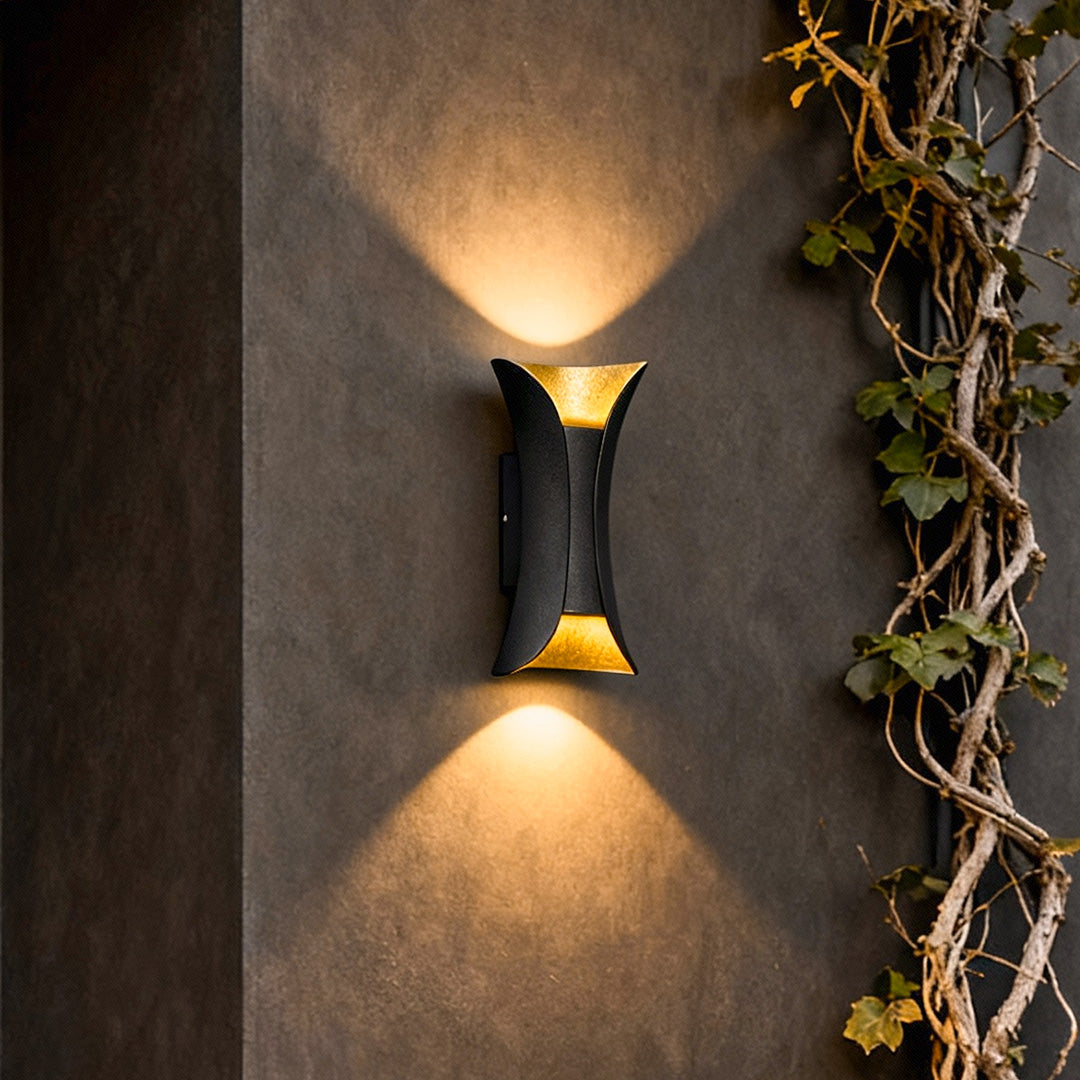 Close up of black and gold up down lighting wall lights highlighting texture on exterior wall with ivy decor.