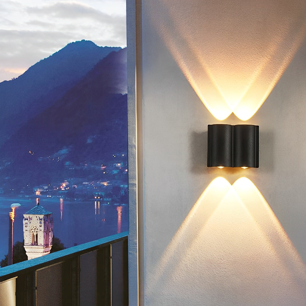 Up and down outdoor wall lights casting warm glow on balcony with scenic lake and mountain view at dusk.