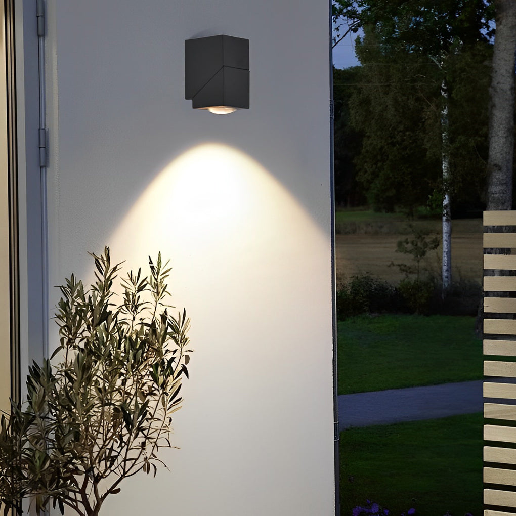 Up down sconce outdoor with dual light heads highlighting white wall and greenery for modern landscape lighting.