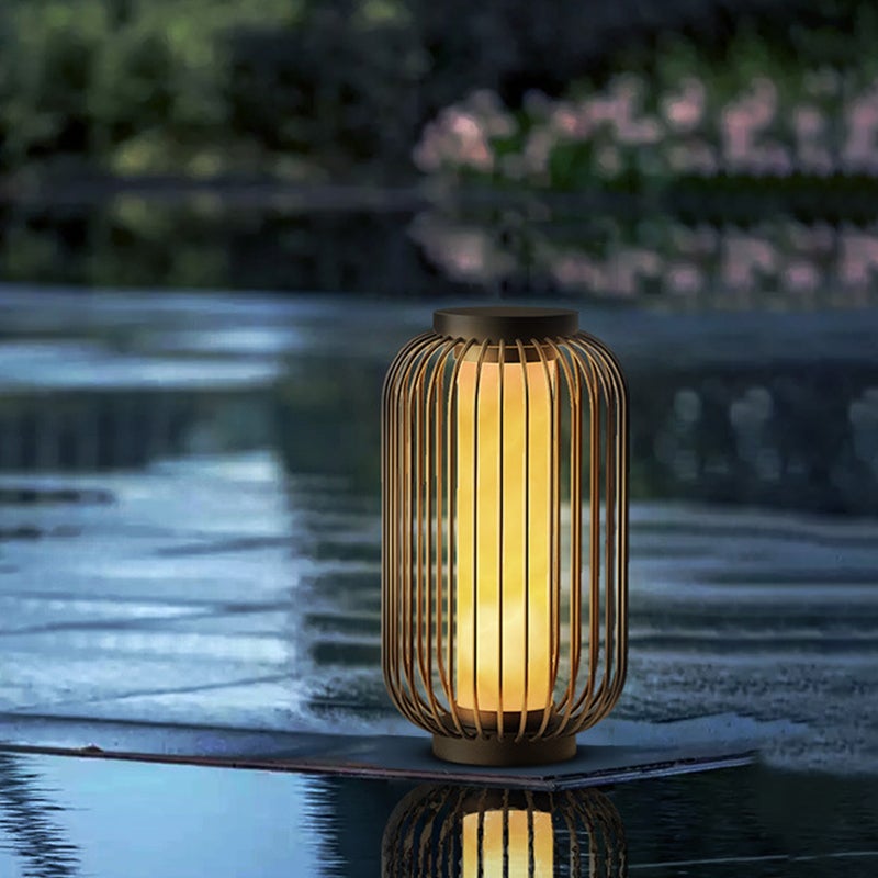 Lantern metal outdoor light with vertical slats, positioned by water for serene and stylish outdoor illumination.