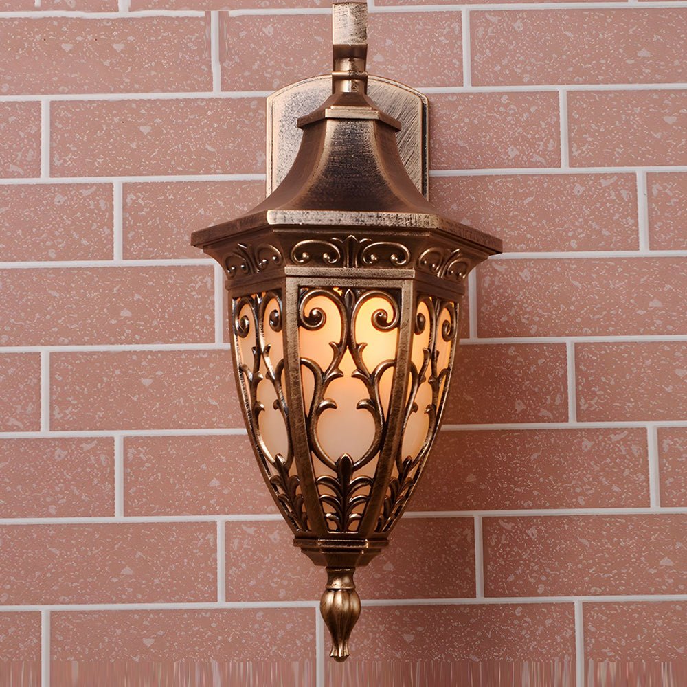 Antique art deco wall sconces with vintage bronze finish, casting a warm glow on a red brick wall exterior.
