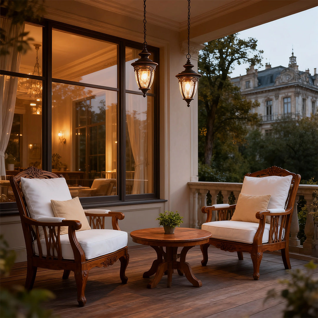 Vintage pendant porch light casting glow on outdoor patio with upholstered chairs at evening