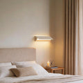 Wall adjustable light installed above bed providing soft ambient bedroom lighting.