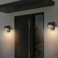 Wall industrial lights mounted on modern gray building with wooden slat accent and house number
