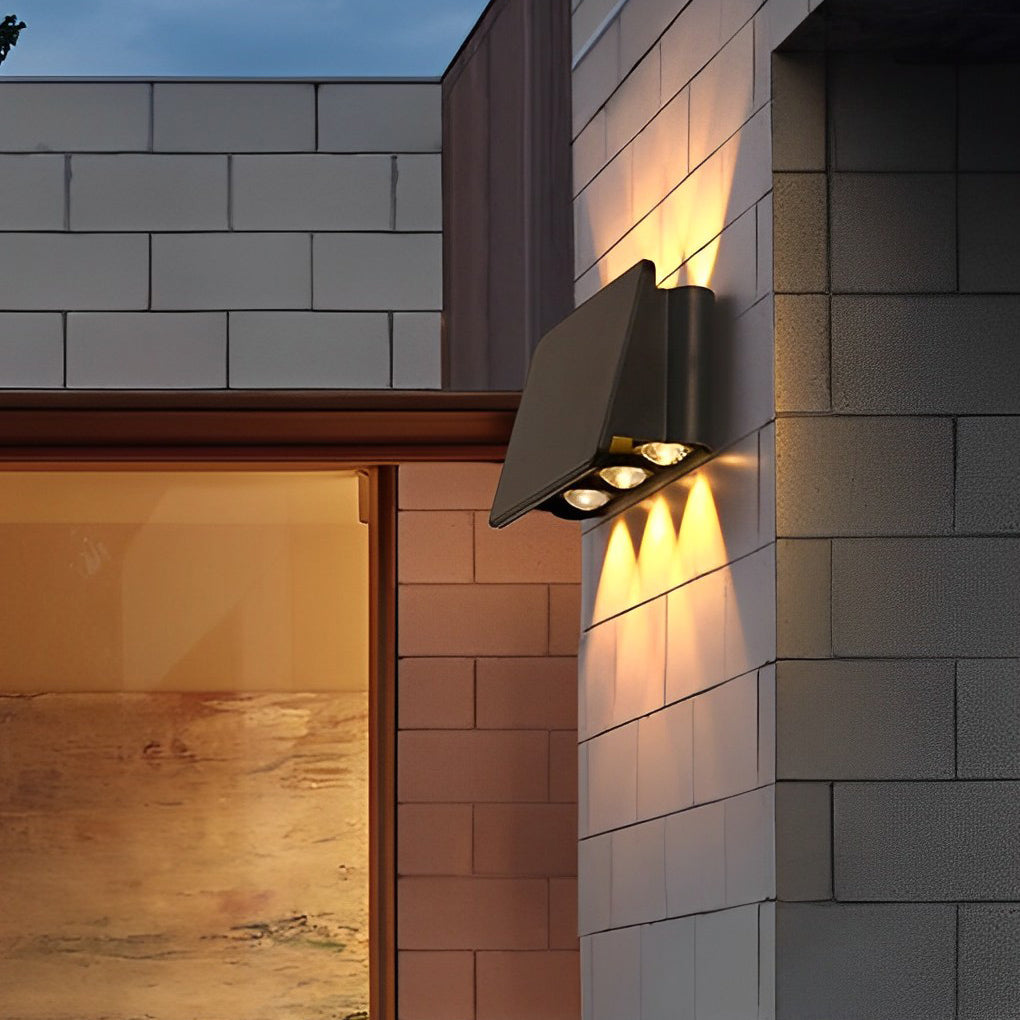 Wall sconce up and down light on brick wall near garden pathway.