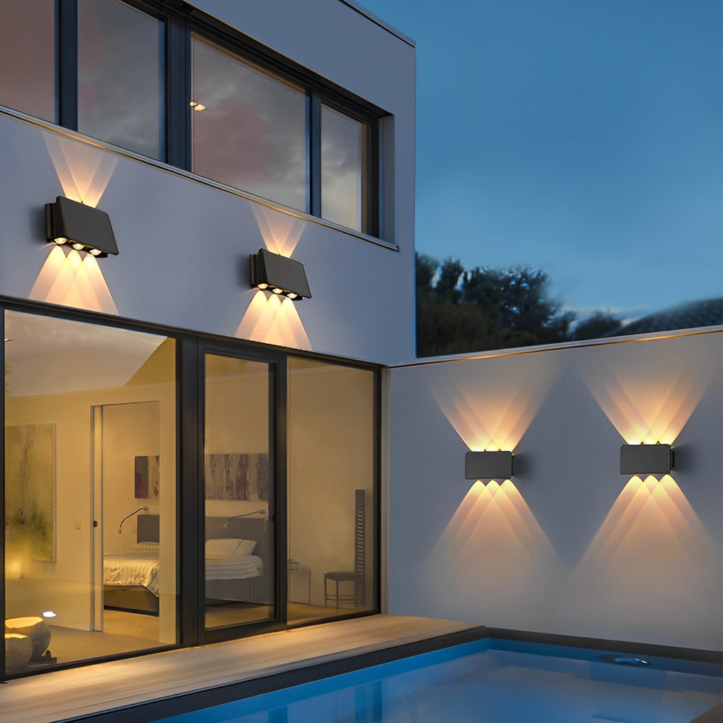 Wall sconce up and down light beside contemporary house with pool view.