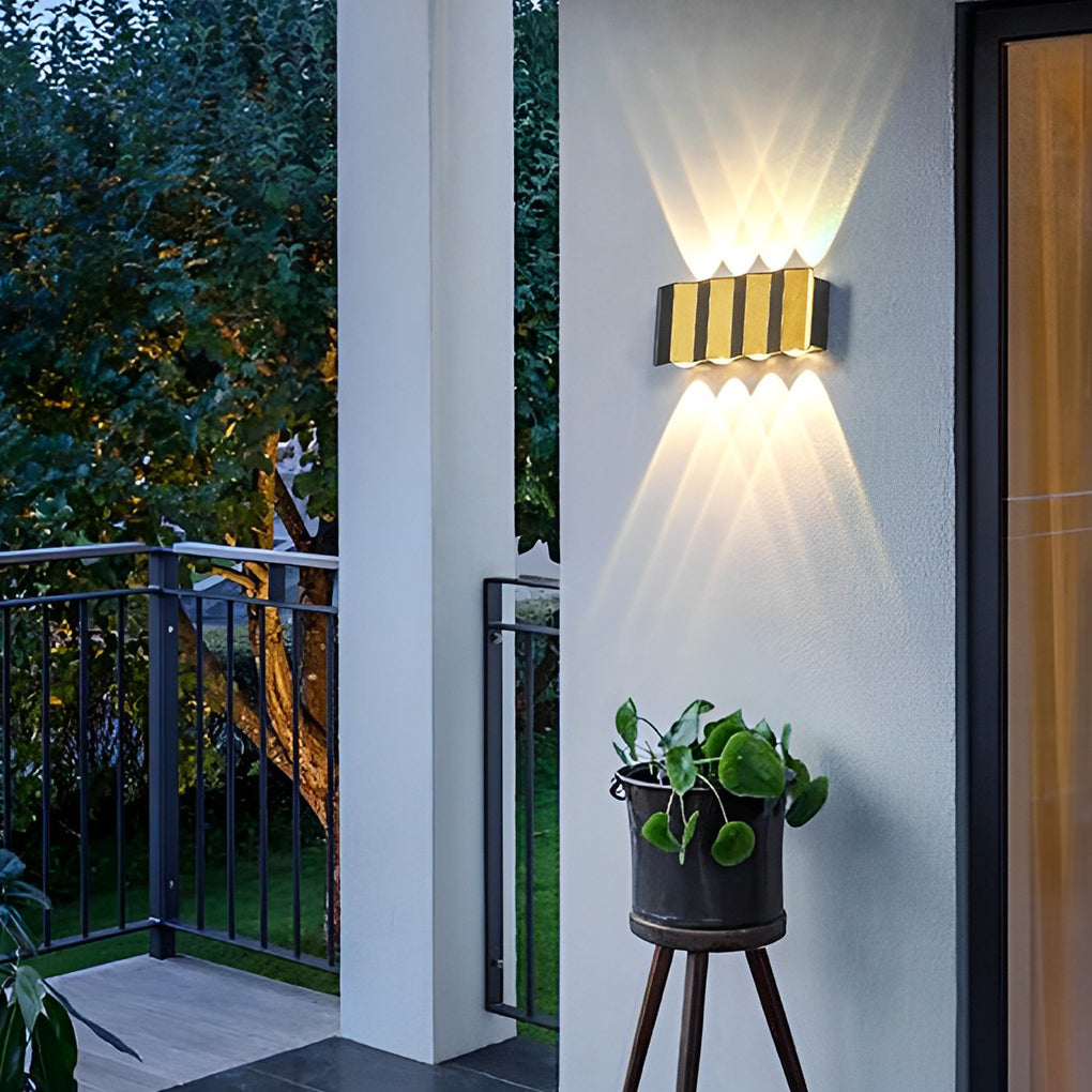 Wall sconce up-down light providing directional light beside a green wall.