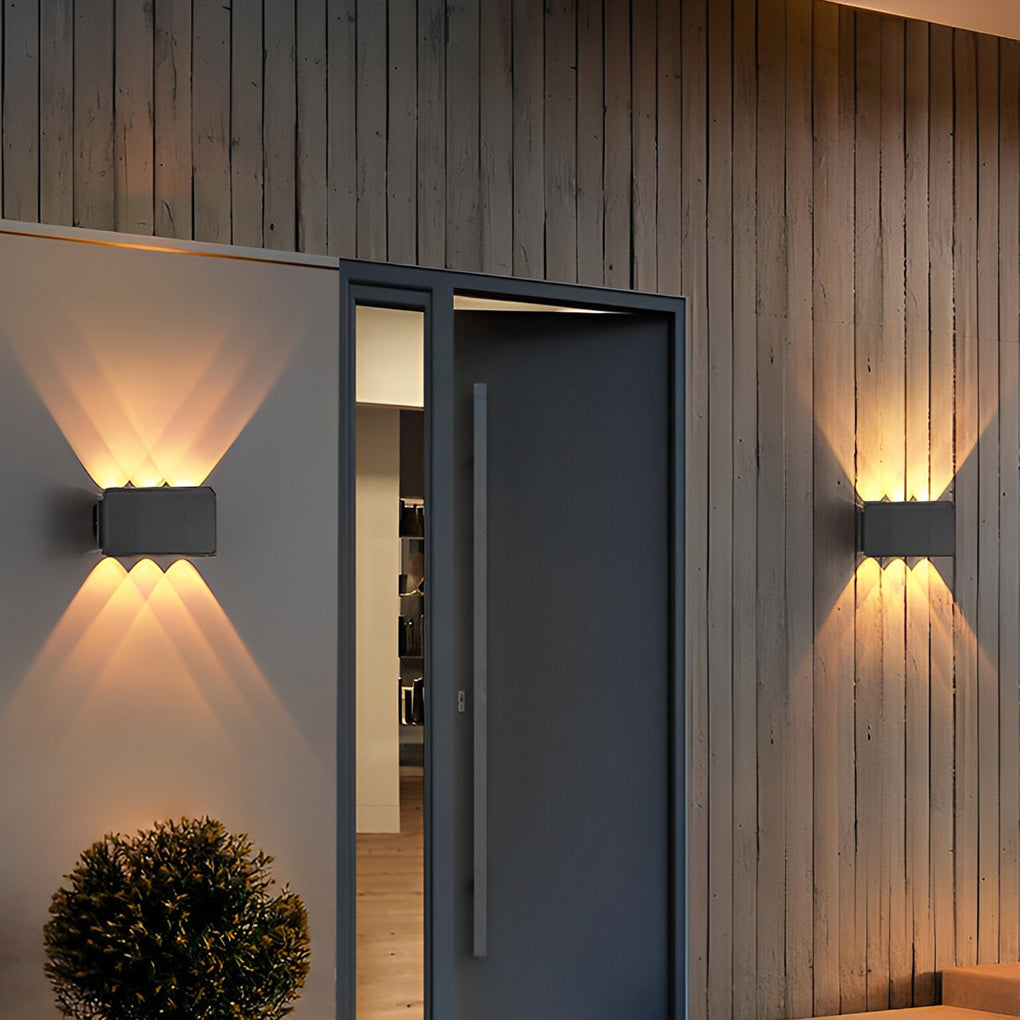 Wall sconce up and down light beside modern house entrance with warm illumination.
