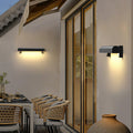 Warm glowing outdoor wall sconce light fixtures installed along a modern exterior walkway at dusk.