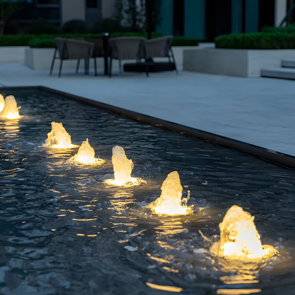 Warm white LED fountain lights floating in swimming pool creating ambient water lighting