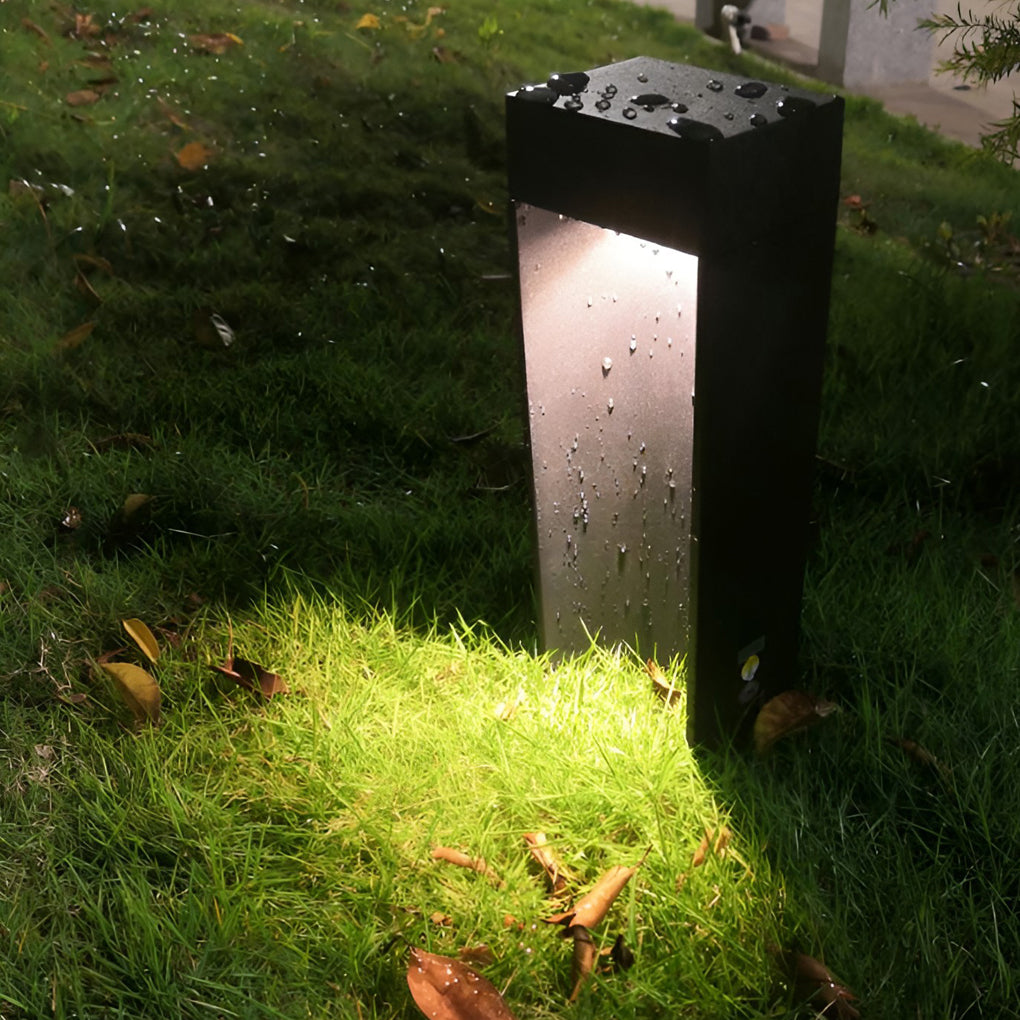 Water-resistant LED bollard light operating in rainy outdoor garden conditions.