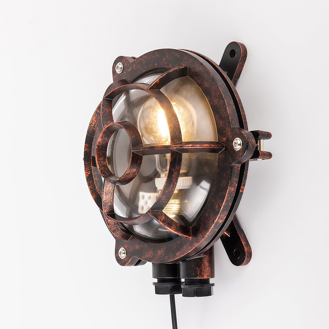 Weathered industrial outdoor sconce with turtle-back design mounted on exterior wall with aged patina