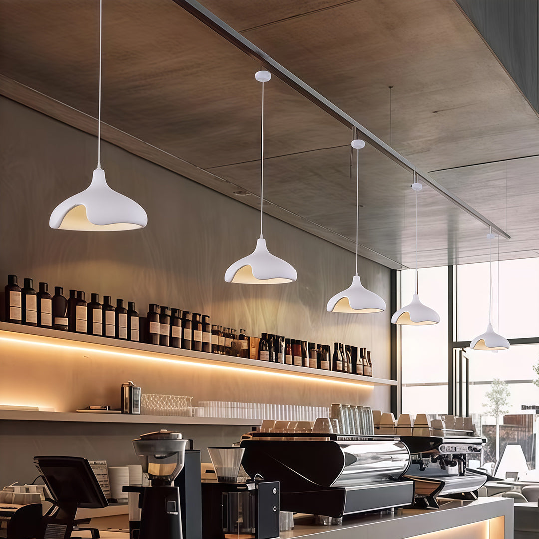 White cement pendant light above dining table in minimalist restaurant with natural lighting.
