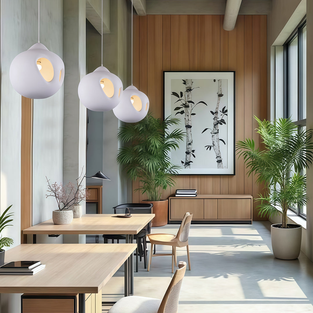 White Nordic wabi sabi pendant light hanging in bright dining space with wooden accents and natural plants.