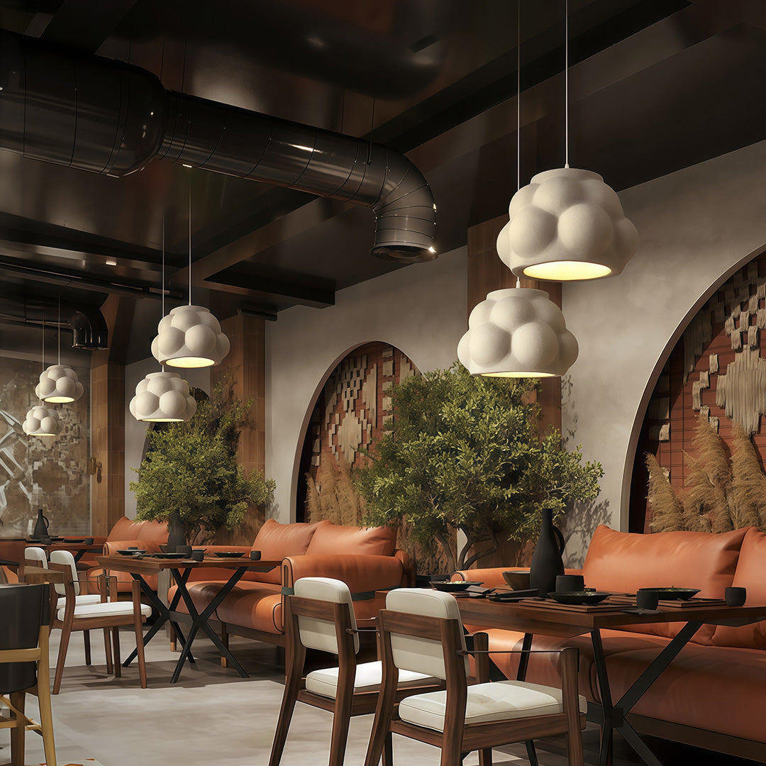 Cluster of white single pendant light fixture hanging above tables in a cozy restaurant interior.