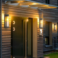 Wooden house facade showcasing a warm amber glow from sleek outdoor wall mount lights flanking the modern front door.